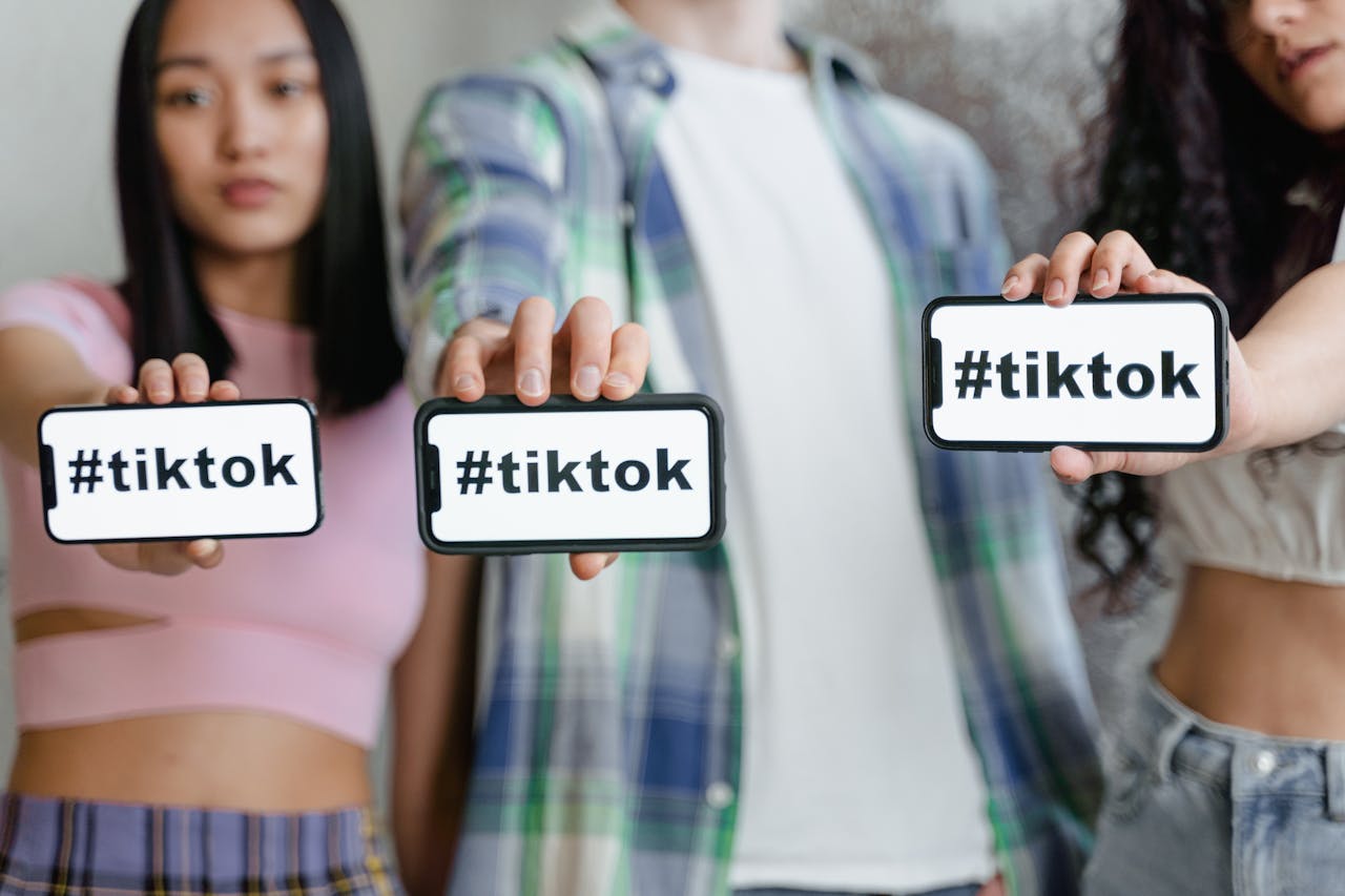 Young adults holding smartphones with TikTok hashtag, showcasing social media engagement.